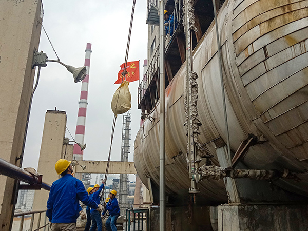 5月10日中午，在動(dòng)力車間三期工藝除氧器地面，黨員突擊隊(duì)隊(duì)員用滑輪往工藝除氧器平臺(tái)運(yùn)送鋼絲網(wǎng)，用以纏繞新填料.jpg