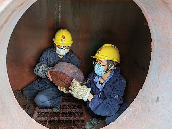 5月11日，動力車間三期工藝除氧器內部，黨員突擊隊隊員劉瑞斌和李震正在清理舊填料.jpg