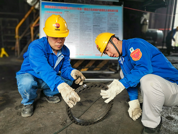 圖三：12日下午14時(shí)，在一期磨煤機(jī)廠房，陜西省技術(shù)能手姬霄給青工張跟潮講解磨煤機(jī)搖臂曲拐內(nèi)環(huán)及動(dòng)作原理。.jpg